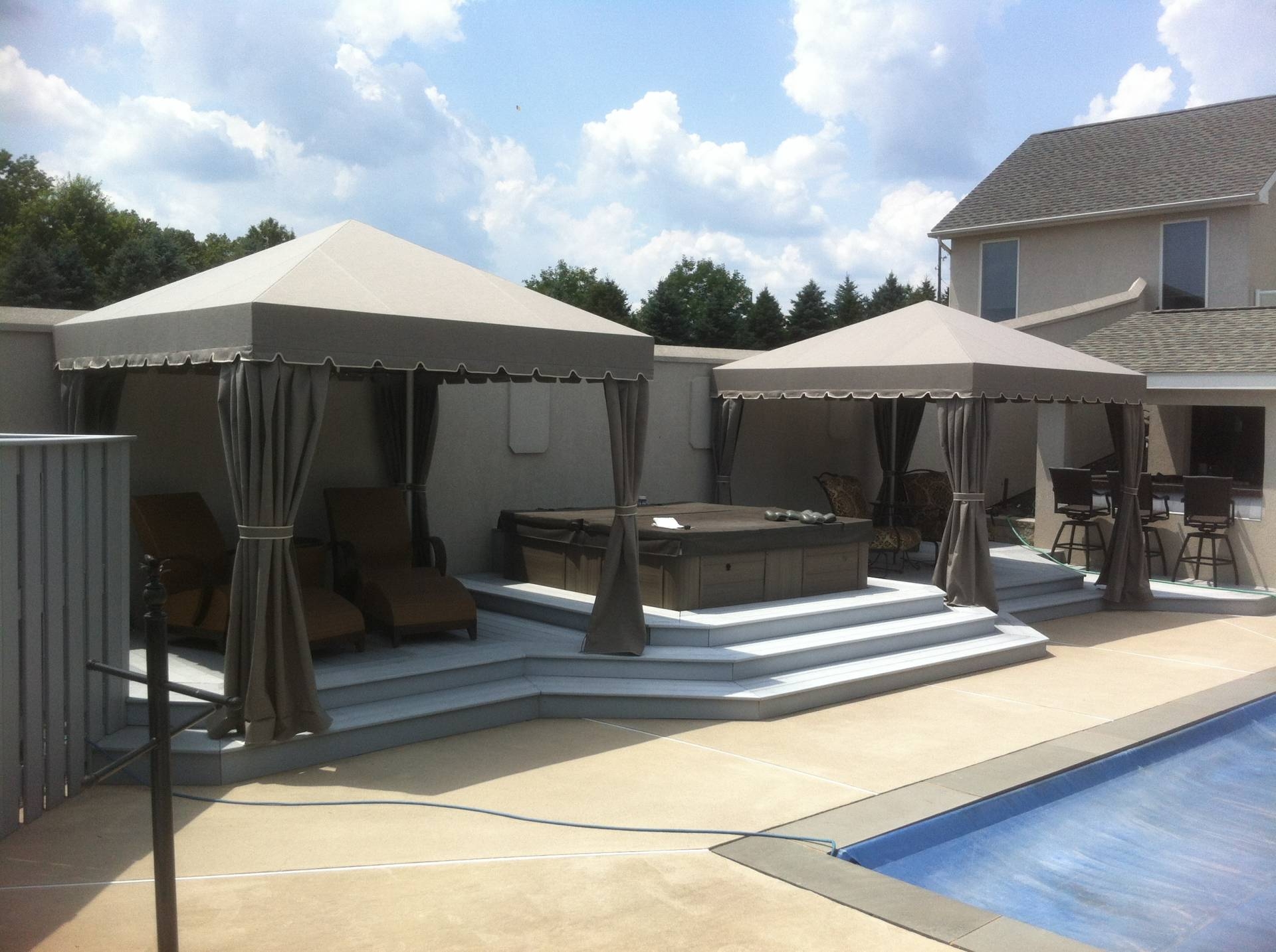Freestanding poolside cabana with corner curtains ...