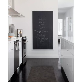 Black-and-white kitchen with large framed chalkboard and practical storage solutions