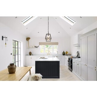 English coach house kitchen with vaulted ceilings, skylights, soft white walls, and black accents on windows, pendant light, island, and stove