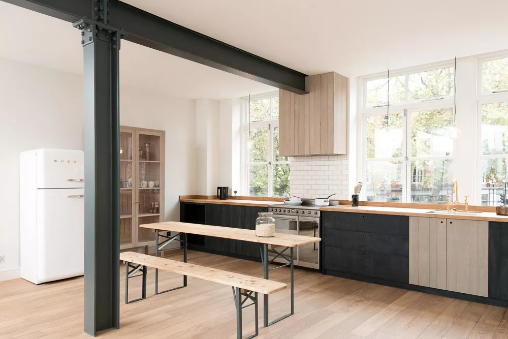 Spacious English loft kitchen with black-and-white theme and dark green beams