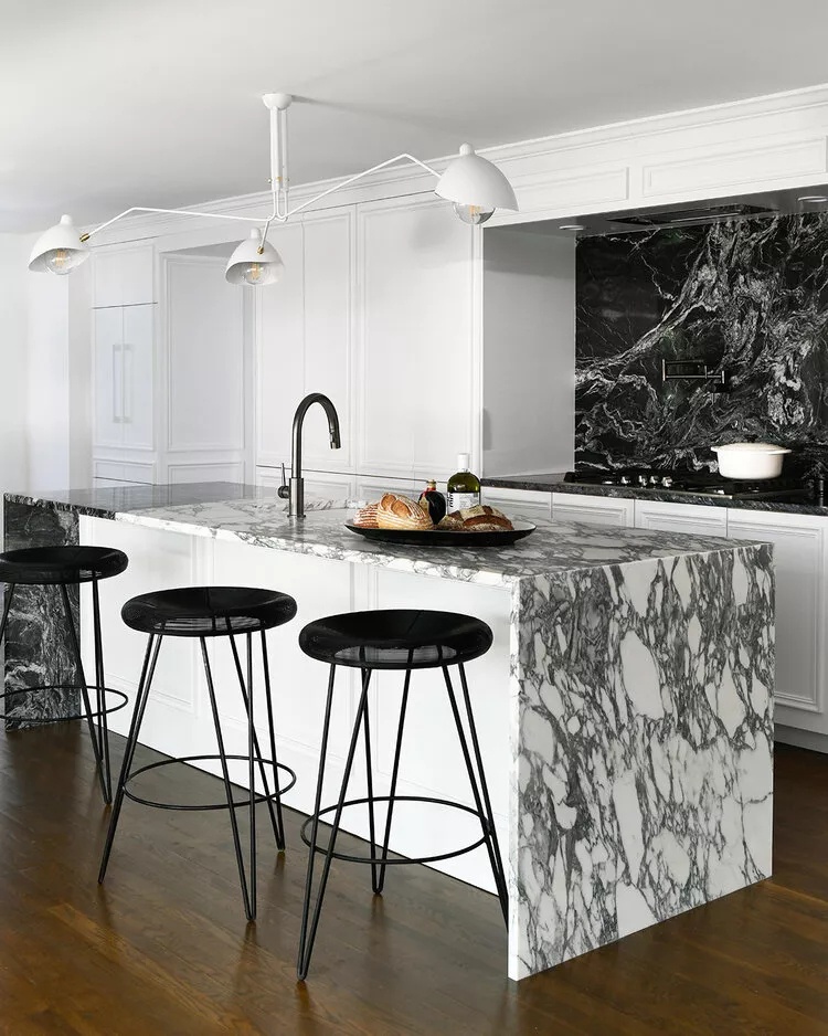 Glamorous black and white marble kitchen with contemporary lighting and warm hardwood flooring