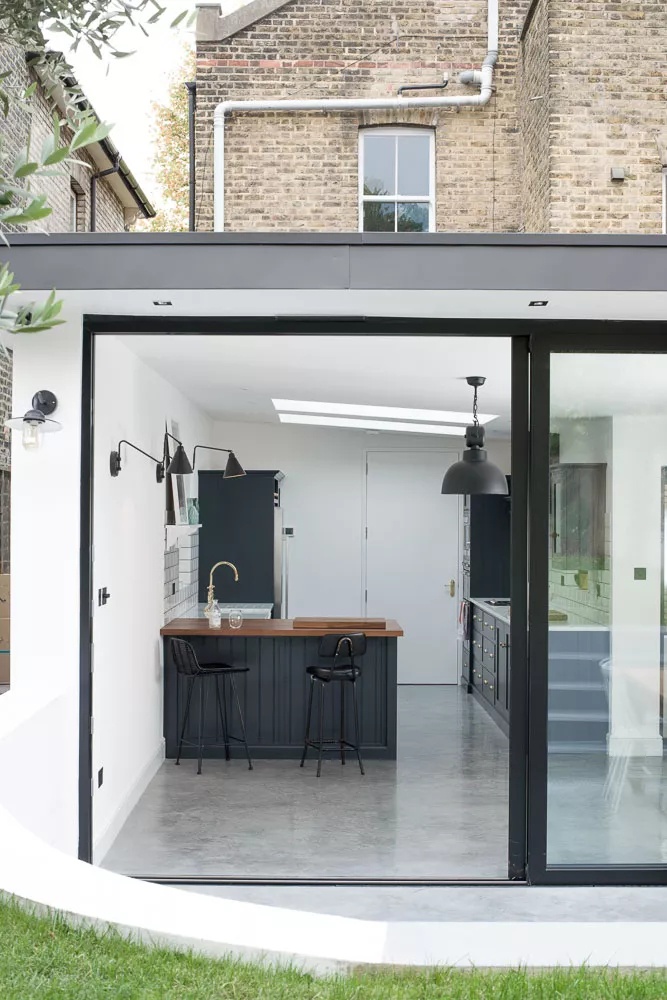 Minimalist black-and-white kitchen extension with industrial edge and gray concrete flooring
