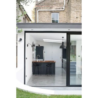 Minimalist black-and-white kitchen extension with industrial edge and gray concrete flooring