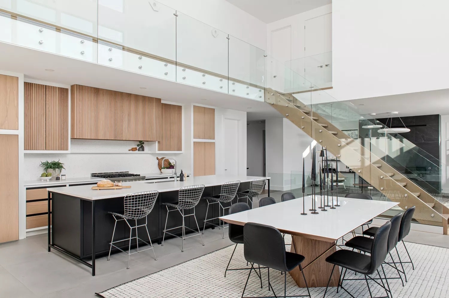 Sprawling open-plan kitchen and dining room with black-and-white palette and wood cabinetry and accents