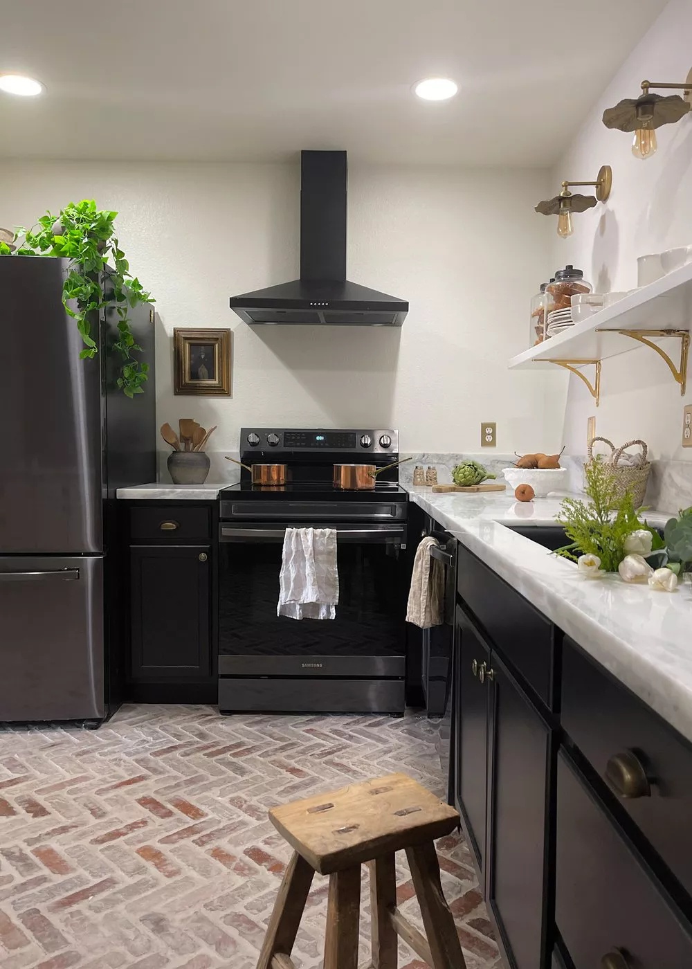 Renovated black-and-white kitchen with brick flooring and ample recessed lighting
