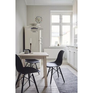 Small eat-in kitchen blending soft whites with black accents and midcentury modern details, like a Danish pendant light, George Nelson wall clock, and Eames Eiffel chairs