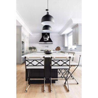 Sprawling kitchen with black pendant lights, white subway tile wall, and black-and-white bar stools