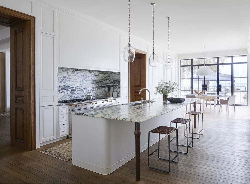 Traditional home kitchen with white cabinetry, black-and-white marble finishes, and antique/vintage-inspired pieces