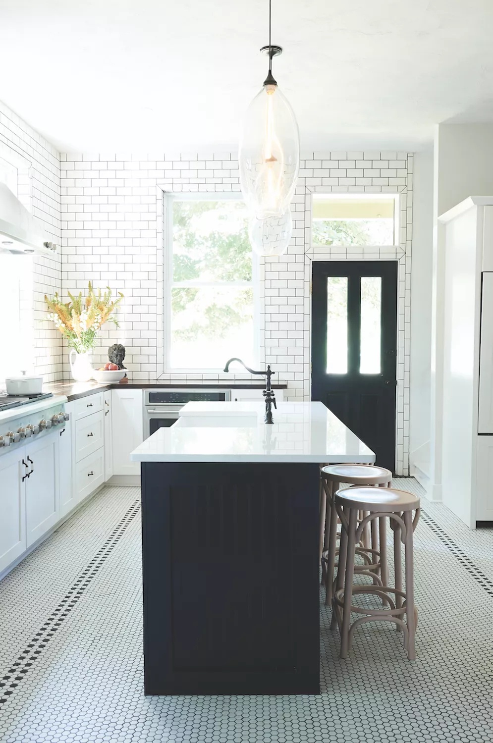 Victorian kitchen with black-and-white penny tiles on the floor, subway tiles on the walls, and black paint on the island and back door