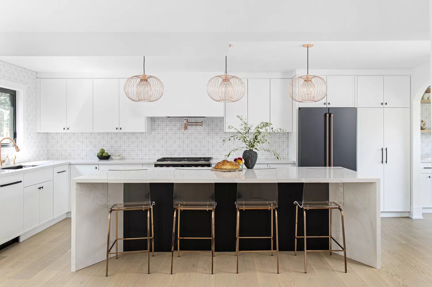 Black and white kitchen with warm metal accents and indoor plants