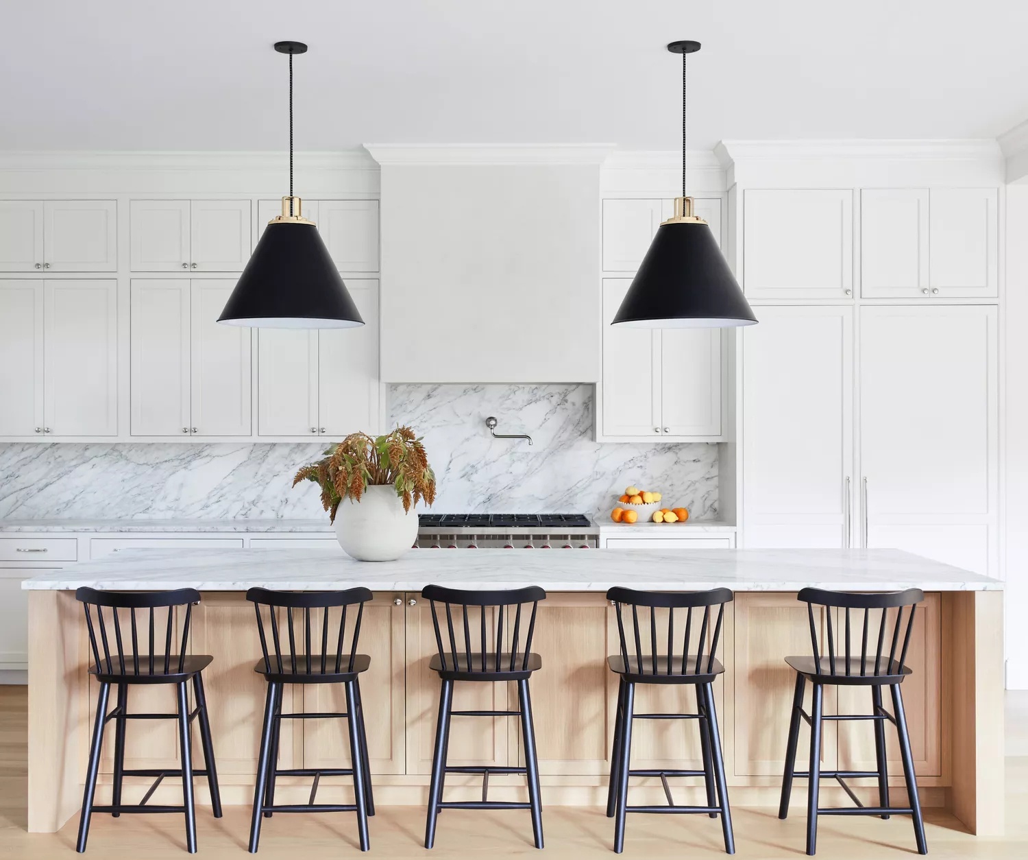 White and pale wood kitchen with Scandi-style black bar stools and pendant lights