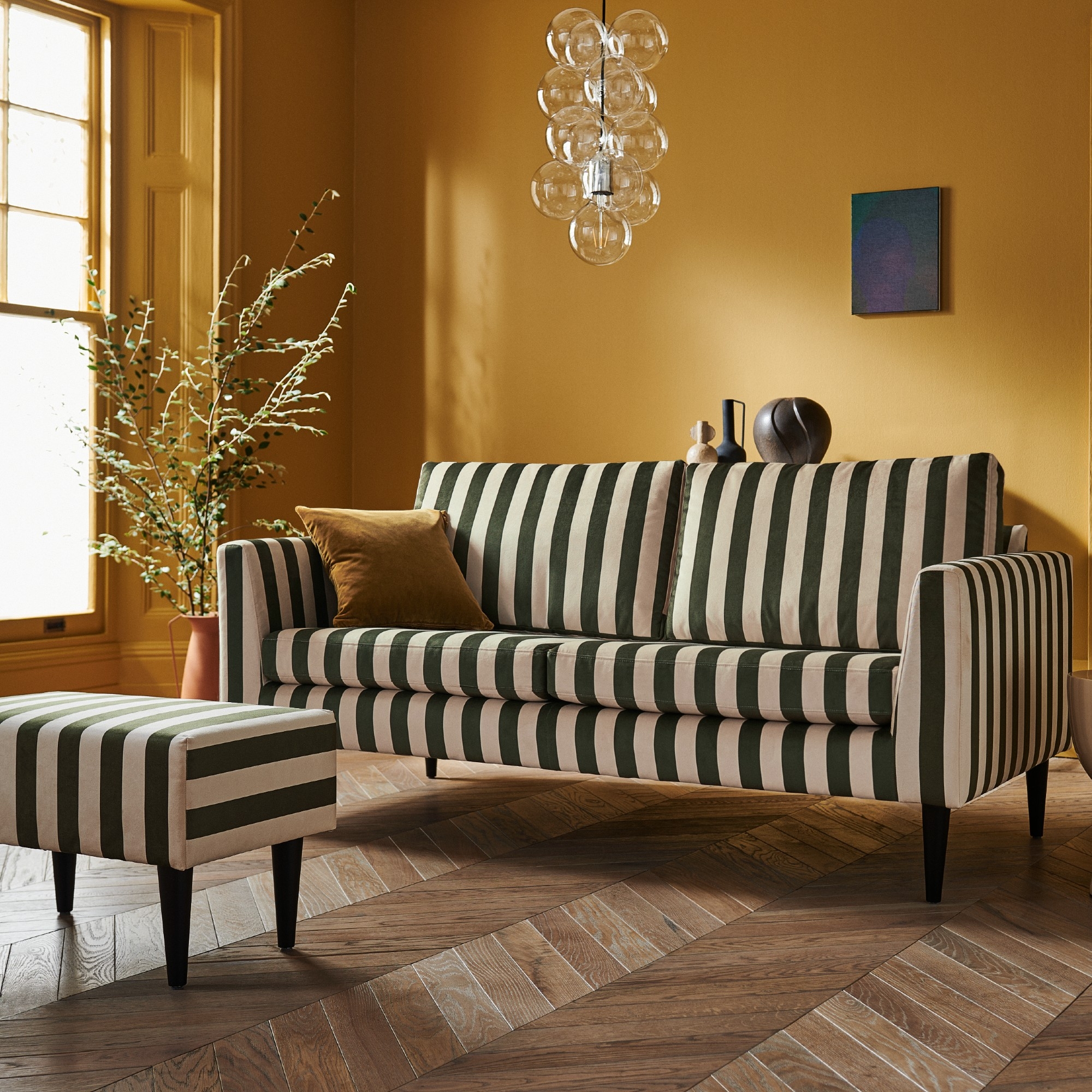 Striped Sofa With Bubble Pendant Light and Ochre Walls