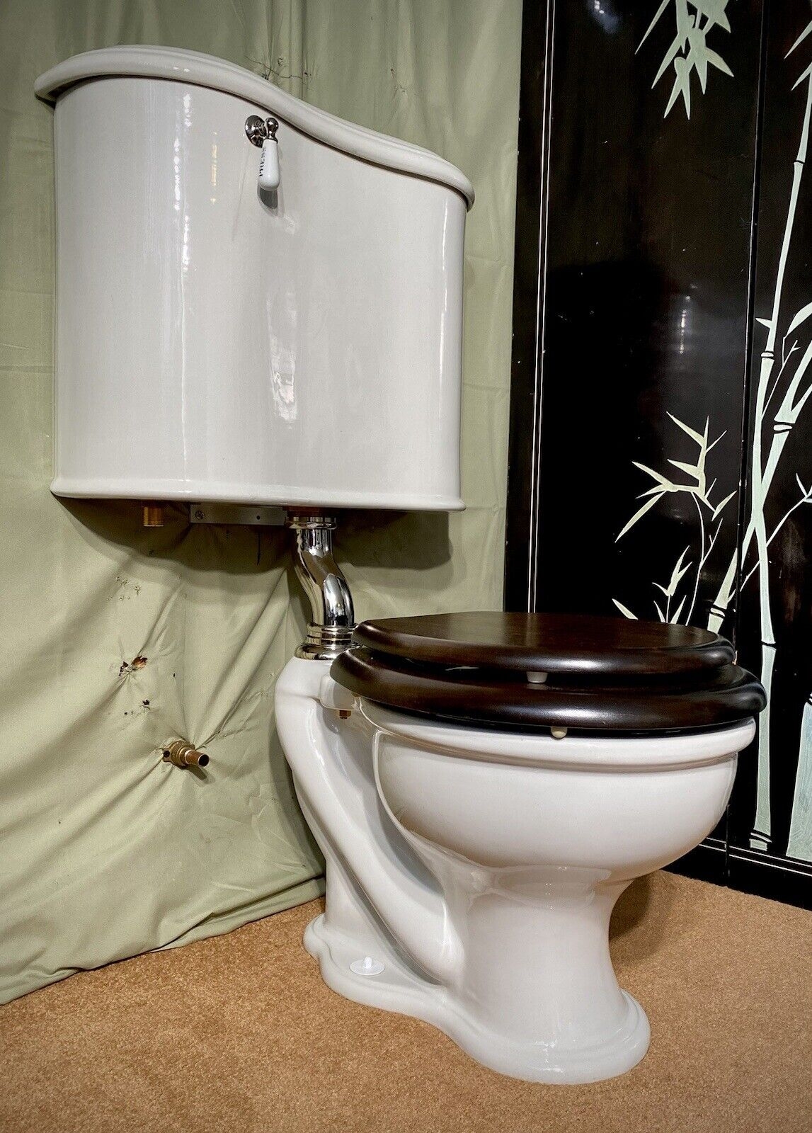 High Tank Toilet utilizes Walnut Toned Seat and Exposed Plumbing Design