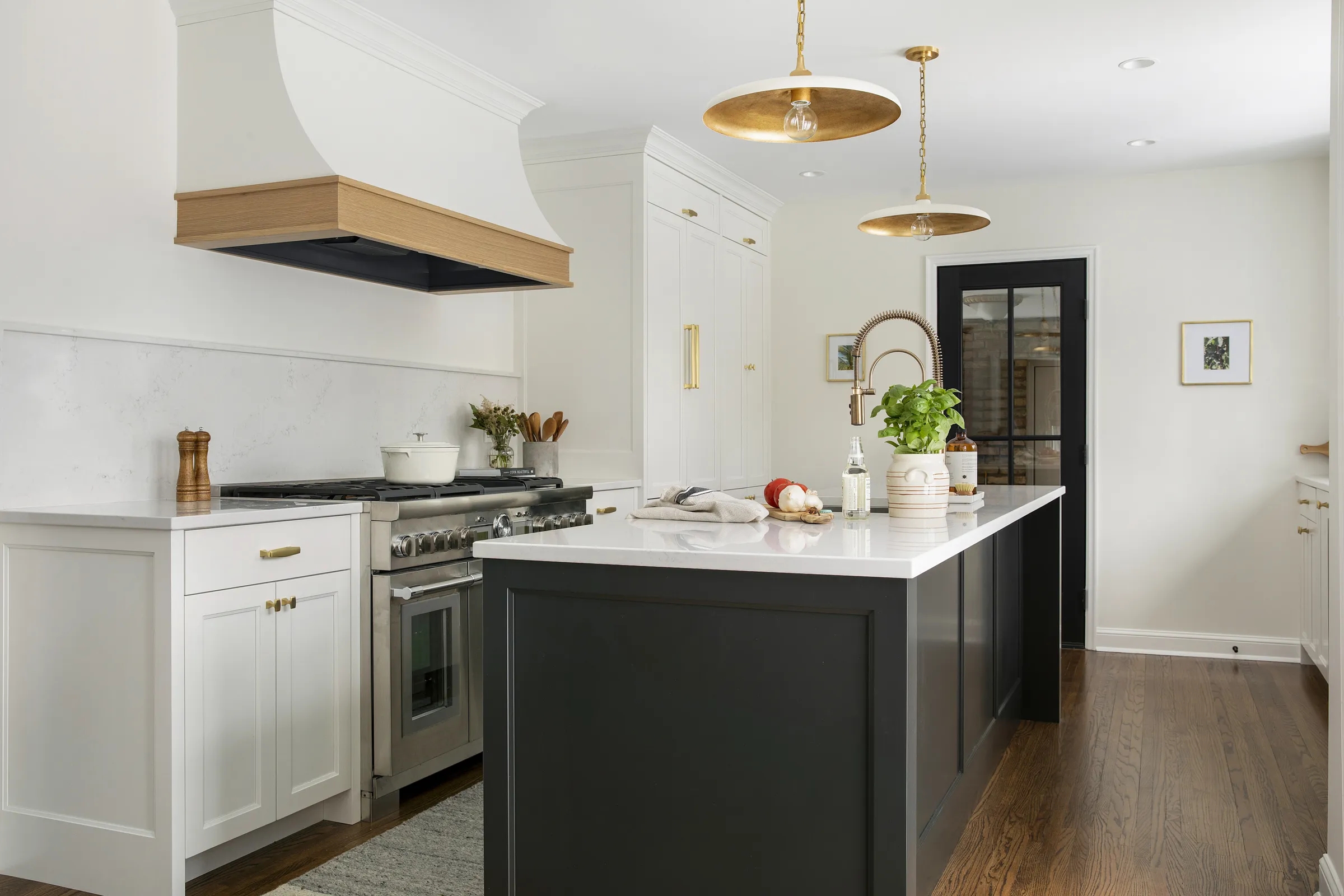 Kitchen Island and Wood Trimmed Range Hood with Gold Pendants