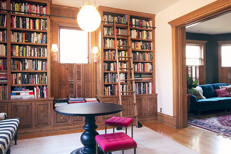 Built In Bookcase with Rolling Ladder and Magenta Tufted Stools