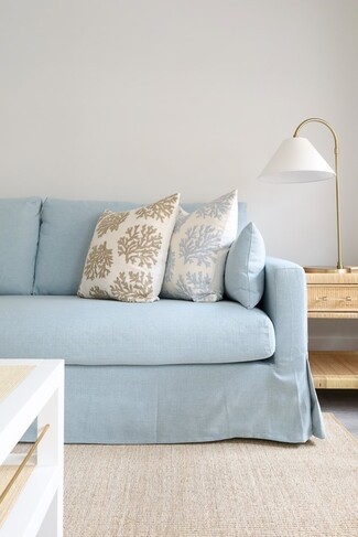 Slipcovered Sofa Pale Blue Upholstery and rattan side table decor