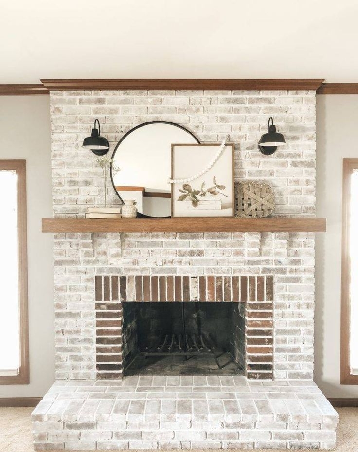Brick Fireplace With Wood Mantel and Matte Black Twin Sconces