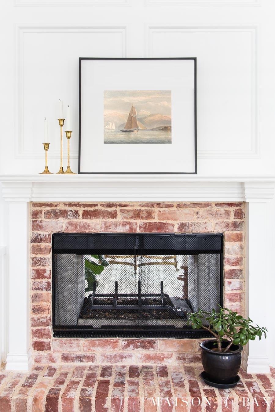 Fireplace Mantel Featuring Tiered Candlesticks and Vintage Art