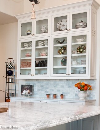 Glass Front Cabinetry with Marble Subway Backsplash and Pot Rack