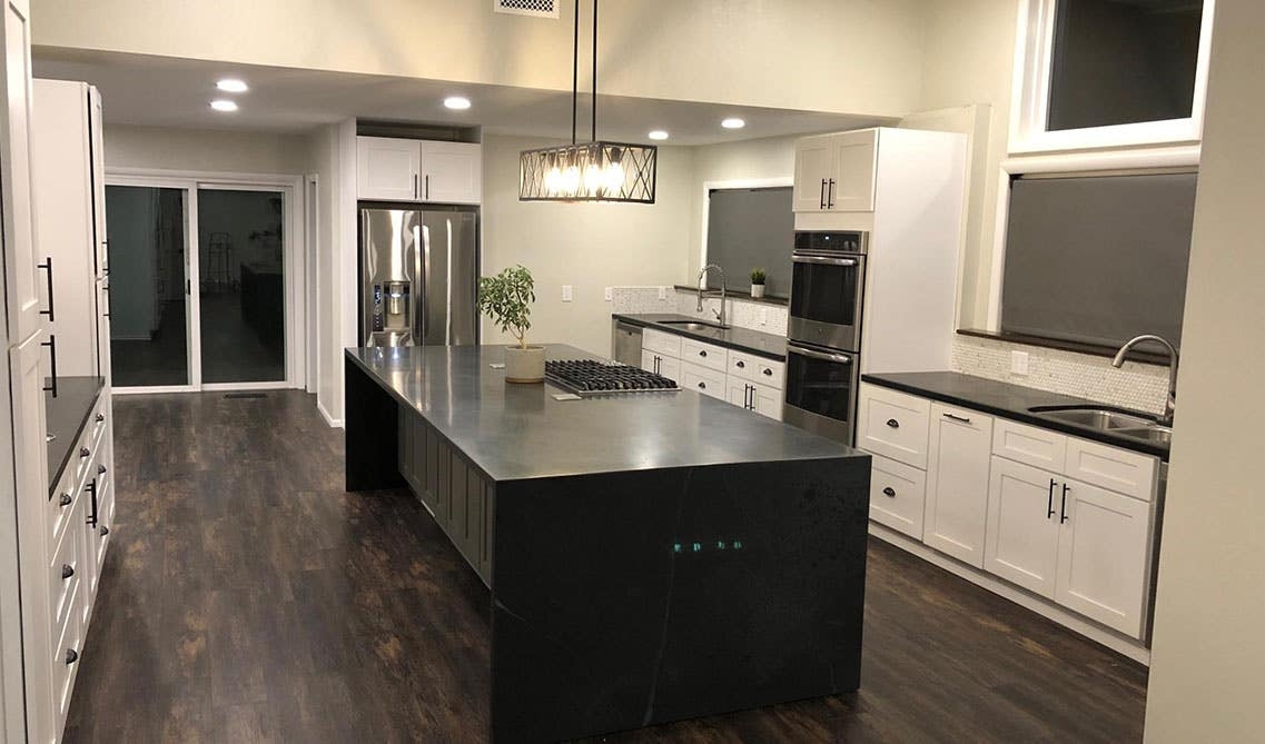 Waterfall Kitchen Island with Black Hardware and Exposed Bulbs