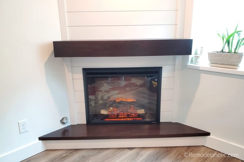 Corner Fireplace With Dark Wood Mantel And Shiplap Backdrop