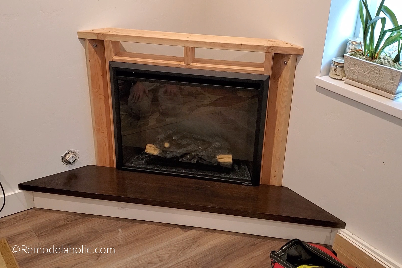 Corner Fireplace With Stained Wood Hearth And Custom Framing